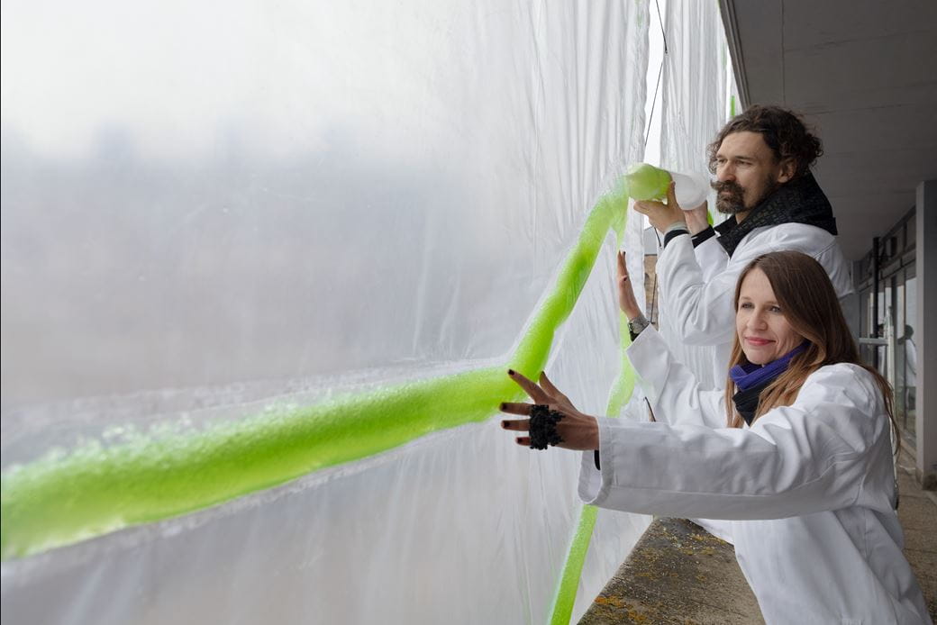 ecoLogic founders Claudia Pasquero and Marco Poletto behind photo.Synthetica algae curtain in Dublin Castle 
